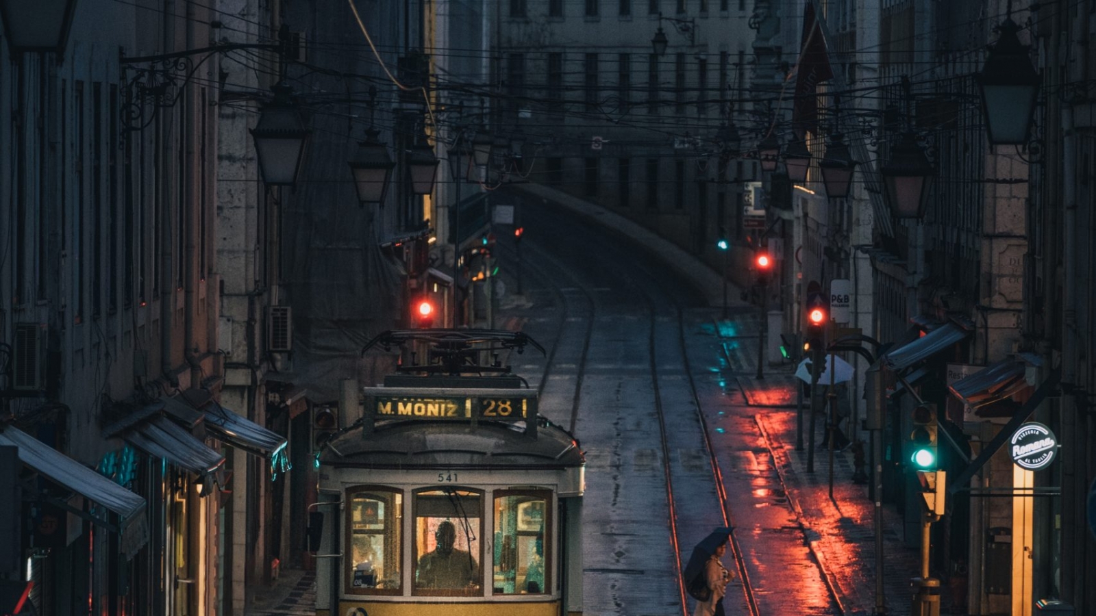 A vertical shot of a tramway as it passes through the buildings of a city during nighttime
